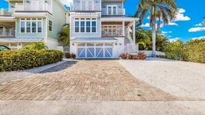 Una casa frente al mar de varios pisos, con garaje, balcón y un jardín cuidado.