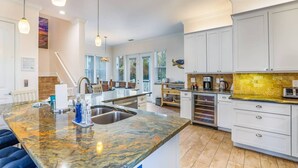 Una cocina amplia con una isla grande, muebles blancos y salpicadero amarillo.