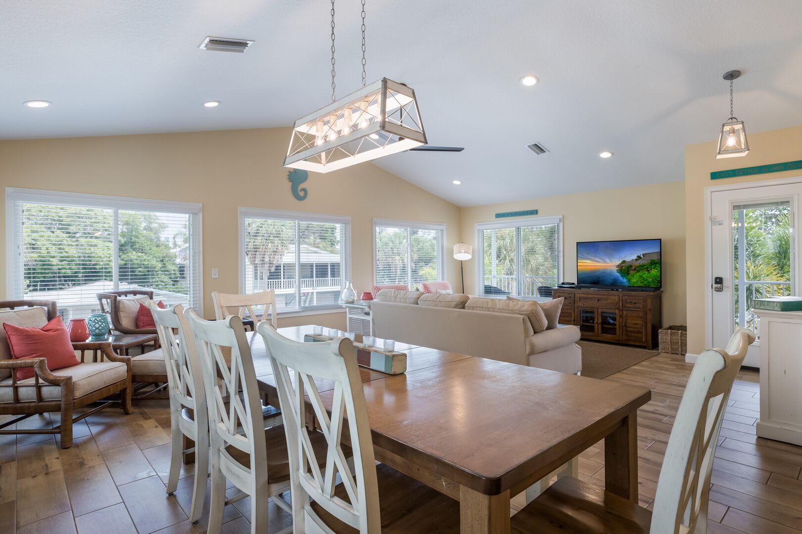 A spacious living area with a dining table, chairs, a sofa, and a television.