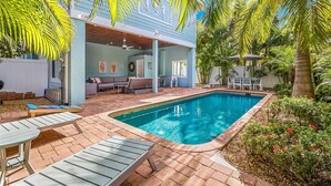Un espace aménagé au bord de la piscine, comprenant une piscine, des chaises longues et un coin salon abrité.