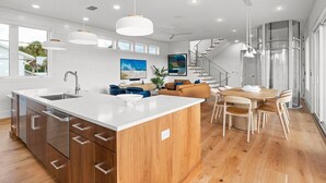Una cucina moderna con una grande isola, mobili in legno e una zona pranzo con tavolo e sedie in legno.