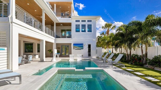 Una moderna casa a due piani con piscina, area salotto esterna e vista sull'oceano.
