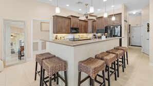 Una cocina moderna con una isla central, taburetes de bar y un ventilador de techo.