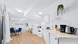 A modern kitchen with white cabinetry, a wooden countertop, and a hanging plant. - Charming 1-bed basement, WI-fi & Pull Out Sofa (Barrie)