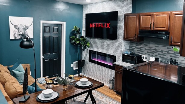 A modern kitchen with a built-in microwave, a large flat-screen TV, and wooden cabinets. - The Cozy Getaway Suite (Philadelphia)