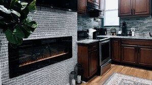 A modern kitchen with dark wooden cabinets, a black backsplash, and a built-in oven. - The Cozy Getaway Suite (Philadelphia)