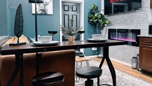 A modern kitchen with a built-in Netflix screen, a decorative wall with a leaf pattern, and a cozy seating area with a leather couch and stools. - The Cozy Getaway Suite (Philadelphia)