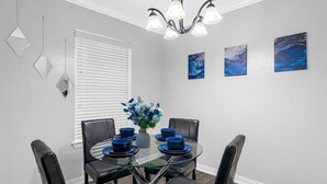 A dining area with a round glass table, black chairs, and a chandelier.