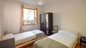 A bedroom with two single beds, a wardrobe, a window with curtains, and a hanging light fixture. - 3 bedroom beautiful apartment in Recco (Recco)