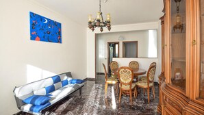 A dining area with a chandelier, a blue abstract painting, a sofa, and a wooden cabinet. - 3 bedroom beautiful apartment in Recco (Recco)