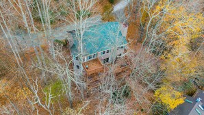 An aerial view of a house surrounded by trees with autumn foliage.