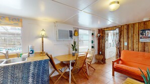Un espacio habitable compacto con kitchenette, comedor y zona de estar.