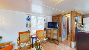 Un espacio habitable compacto con televisor, zona de estar y una pequeña kitchenette.