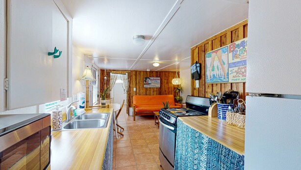 Cocina compacta con lavaplatos, estufa y una zona de comedor de madera.