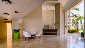 Eine Hotelhalle mit Rezeption, Sitzgelegenheiten und einer großen Pflanze in einem Topf.