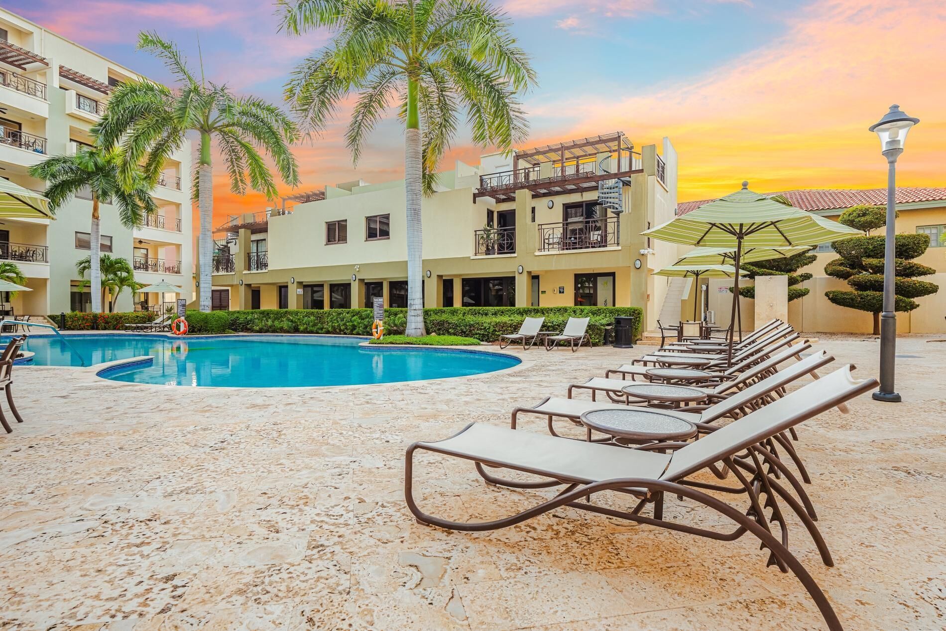A resort pool area with lounge chairs and palm trees.