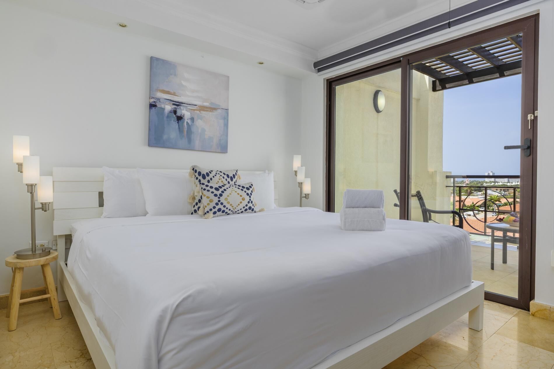 Un dormitorio con cama, un cuadro, una mesita de noche y vistas al exterior.