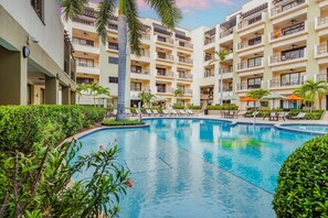 Un hotel a più piani con piscina centrale circondata da poltroncine e ombrelloni.