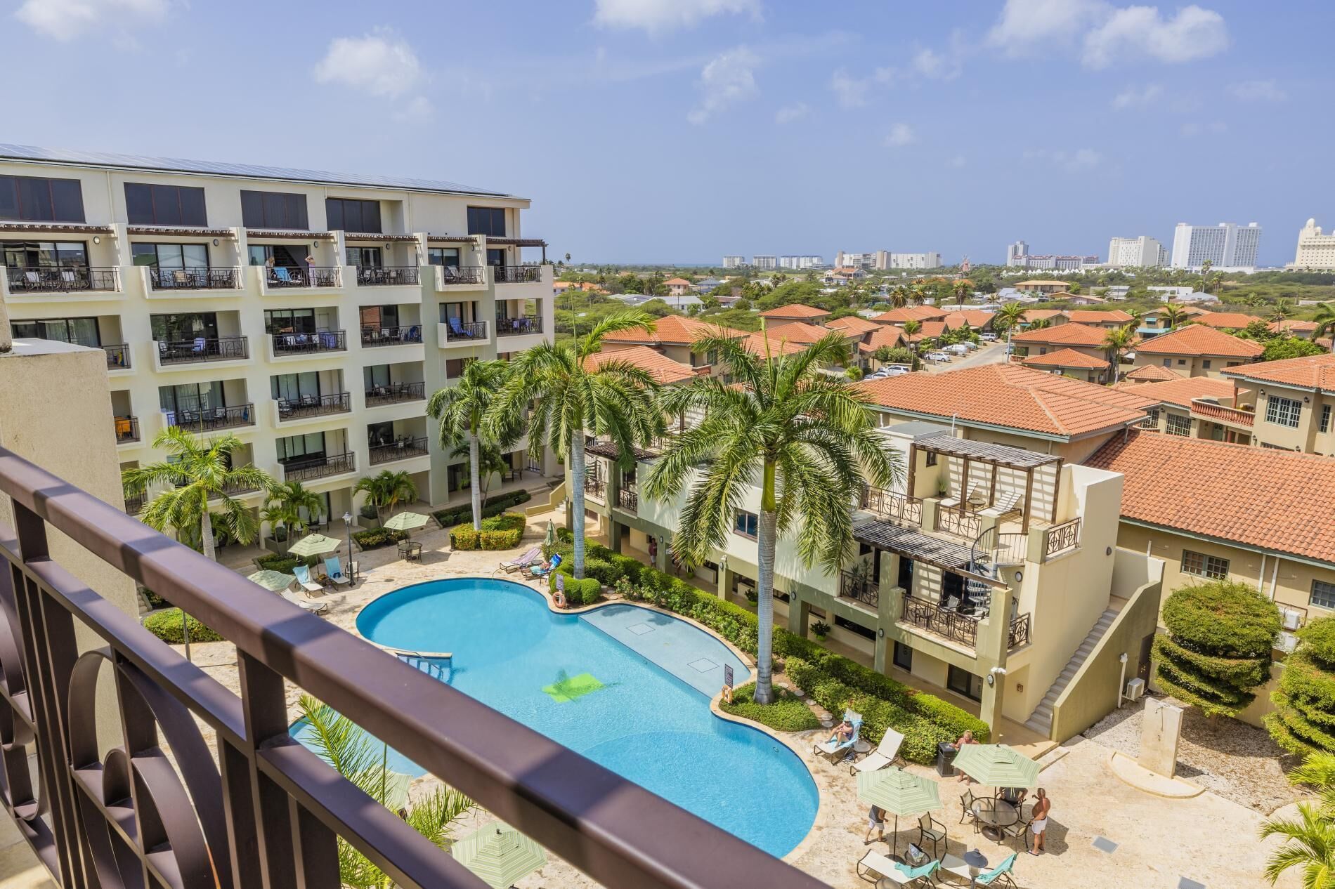 A hotel with a swimming pool, multiple balconies, and a view of the cityscape.