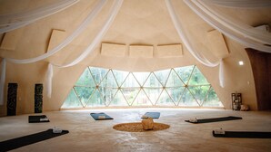 A spacious room with a high ceiling, large windows, and yoga mats arranged on the floor. - Alma Maya Resort – Riviera Maya (Puerto Morelos)
