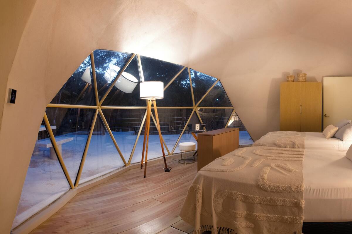 Una habitación acogedora con cama, escritorio y un amplio ventanal con vistas al cielo nocturno.