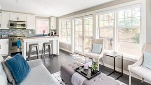 Eine moderne Küche mit weißen Schränken, Edelstahlgeräten und einem großen Fenster mit Blick auf einen Garten.