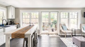 Eine moderne Küche mit einer zentralen Kochinsel, großen Fenstern und einem Balkon.