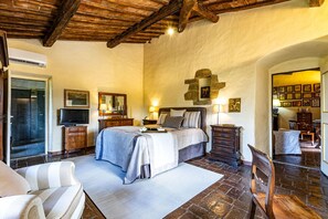 Een slaapkamer met een groot bed, een houten garderobe, een nachtkastje, een spiegel en een decoratieve stenen muur.