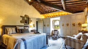 Une chambre avec un grand lit, un plafond en bois, une petite table et une chaise.