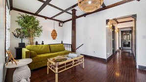 Un soggiorno con un divano verde, un tavolino in legno, una pianta grande e un lampadario.