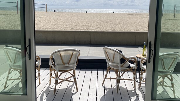 A beach view from a balcony with wicker chairs and a table, overlooking the sand and sea. - Modern 2BDRM/2BATH Beachfront Condo in Hermosa (Hermosa Beach)