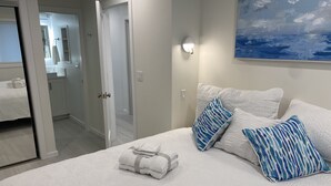 A bedroom with a bed, white bedding, and a painting on the wall. - Modern 2BDRM/2BATH Beachfront Condo in Hermosa (Hermosa Beach)