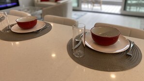 A dining table with two red bowls and clear glasses, set with a placemat. - Modern 2BDRM/2BATH Beachfront Condo in Hermosa (Hermosa Beach)