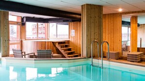 Piscina interna com paredes de madeira e escada que leva a um espaço de deck.