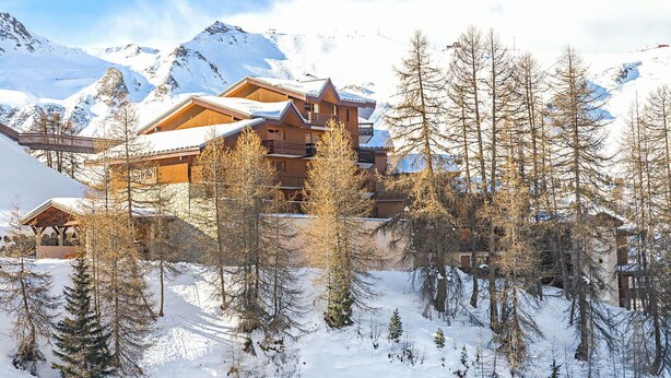 A large lodge with multiple wooden buildings surrounded by snow-covered mountains and trees. - Beautiful apartment for 6 guests with pool, WIFI, TV, terrace and pets allowed (La Plagne)