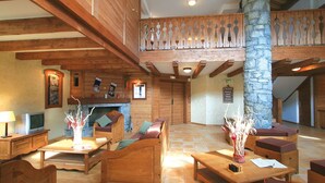 A wooden-floored lobby with a fireplace, seating area, and a stone pillar. - Beautiful apartment for 8 people with pool, WIFI, TV, terrace and pets allowed (Vallandry)