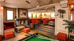 Ein gemütliches Lodge-Interieur mit Kamin, Sitzecke und Billardtisch.