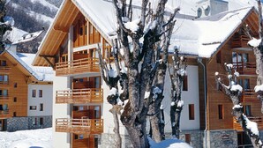 Uma cabana coberta de neve com várias varandas de madeira e base de pedra.