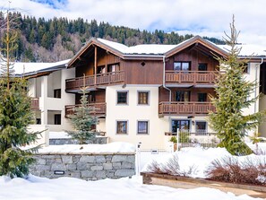 Un edificio de madera de varios pisos con balcones, rodeado de nieve y árboles.