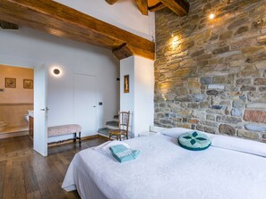 Cozy retreat with a comfortable bed, wooden chair, and small bench for relaxation.