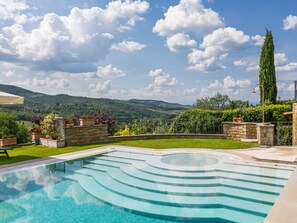 Relax by the serene pool surrounded by lush greenery and rolling hills.