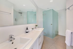 A modern bathroom with two sinks, a large mirror, and a glass-enclosed shower. - Top 1 Sunshine Beach Family Retreat (Sunshine Beach)