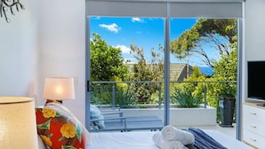 A bedroom with a bed, a lamp, a view of the outdoors, and a TV on a dresser. - Top 1 Sunshine Beach Family Retreat (Sunshine Beach)