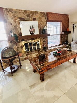 A living room with a stone fireplace, a coffee table, and a lamp.