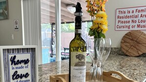 A kitchen counter with a bottle of wine, a vase with flowers, a wooden tray, and a framed sign. - Frenzy for the old w/heatedpool in a safe and quite neighborhood! (Tampa)