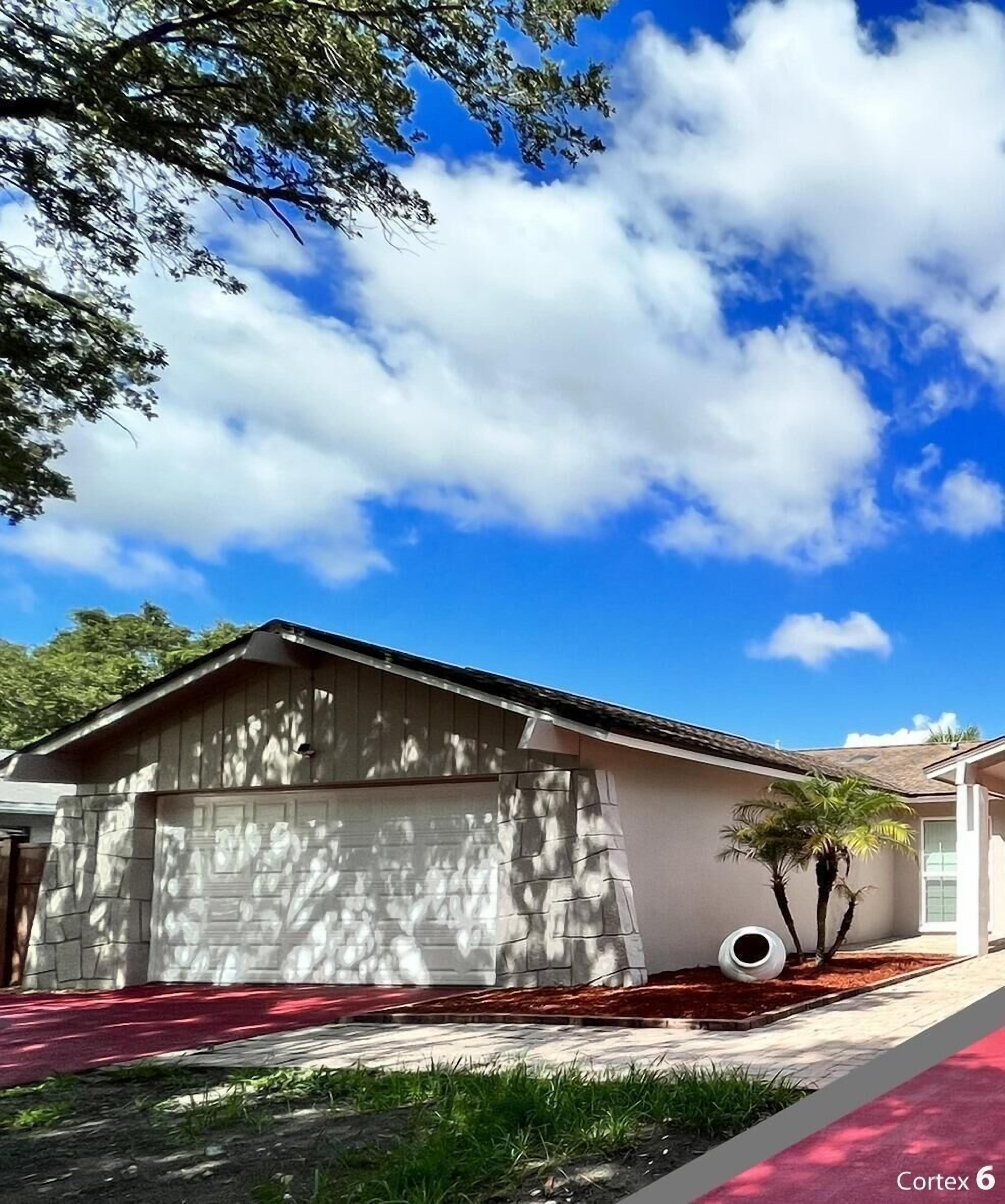 A single-story house with a garage, a small tree, and a tire in the driveway.