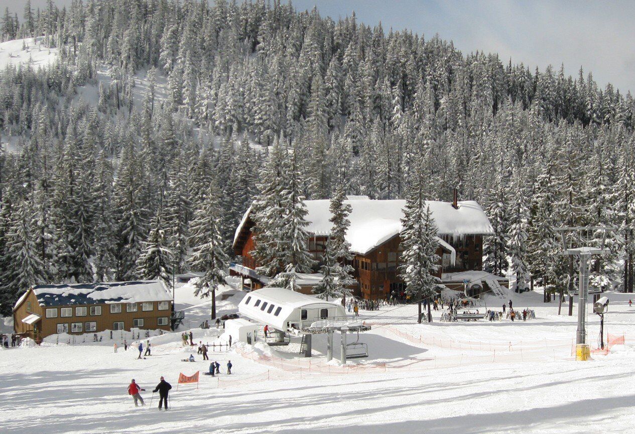 A ski resort with a lodge, ski lift, and snow-covered trees.