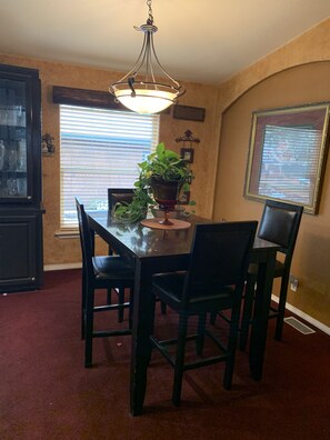 A dining area with a table, chairs, a chandelier, and a potted plant.
