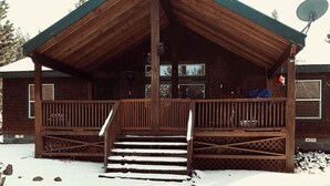 A wooden cabin with a porch and steps leading to the entrance. - Great family getaway with large entertaining deck. (Crescent Lake)