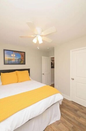 Relax in a cozy retreat with a neatly made bed, ceiling fan, and artwork on the wall.